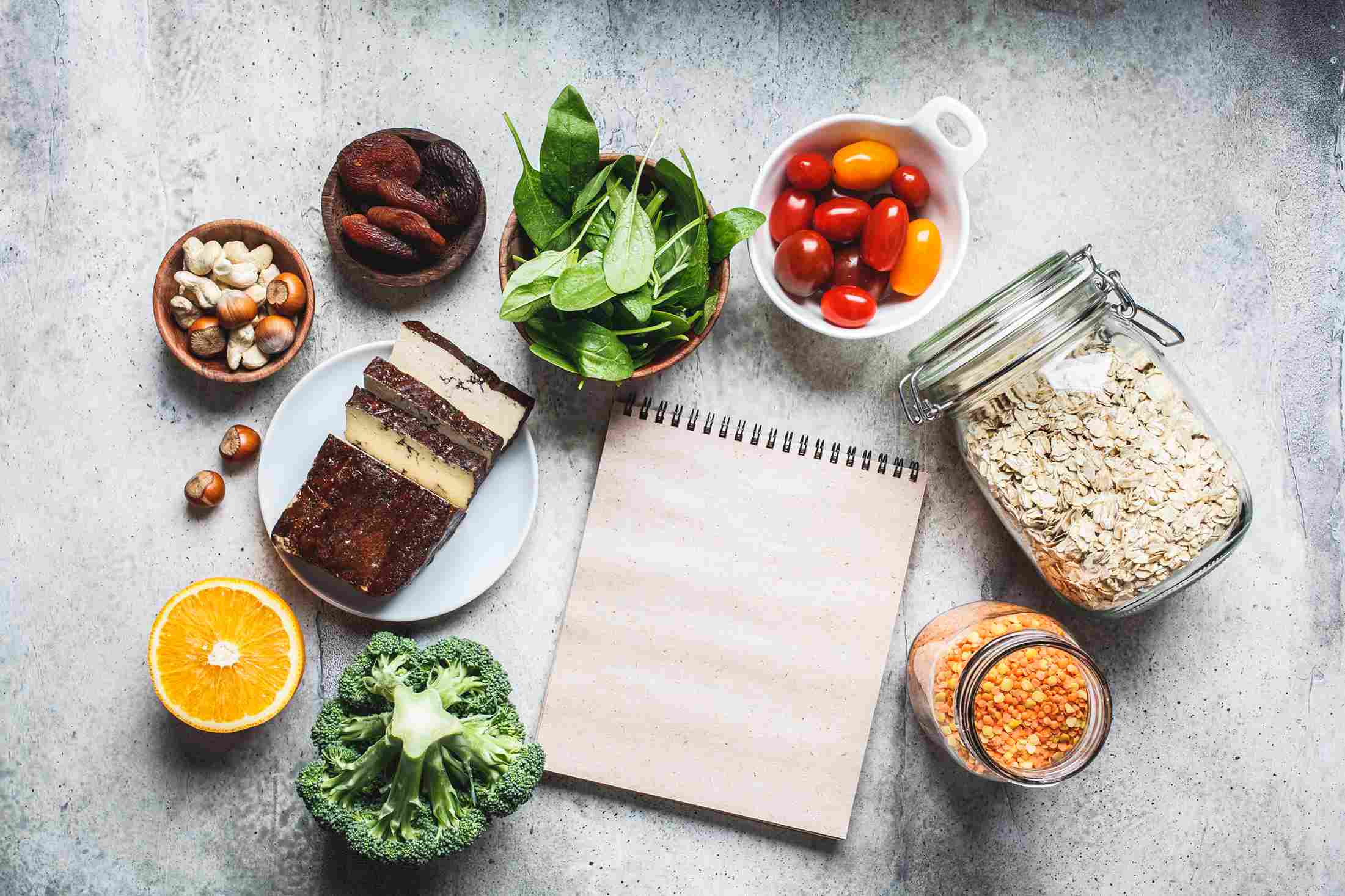 Različite zdrave namirnice raspoređene oko prazne sveske na stolu