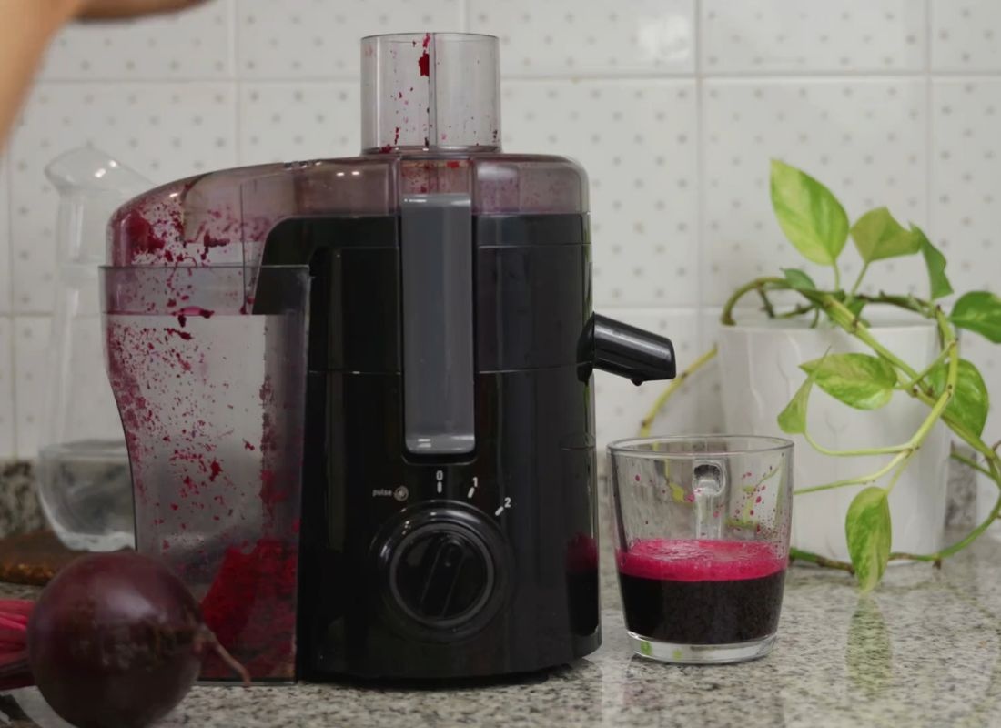 Sokovnik sa sokom od cvekle i čaša na kuhinjskom pultu