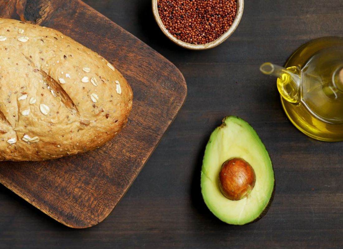 avokado, hleb, maslinovo ulje i čili u činiji postavljeni na drveni sto