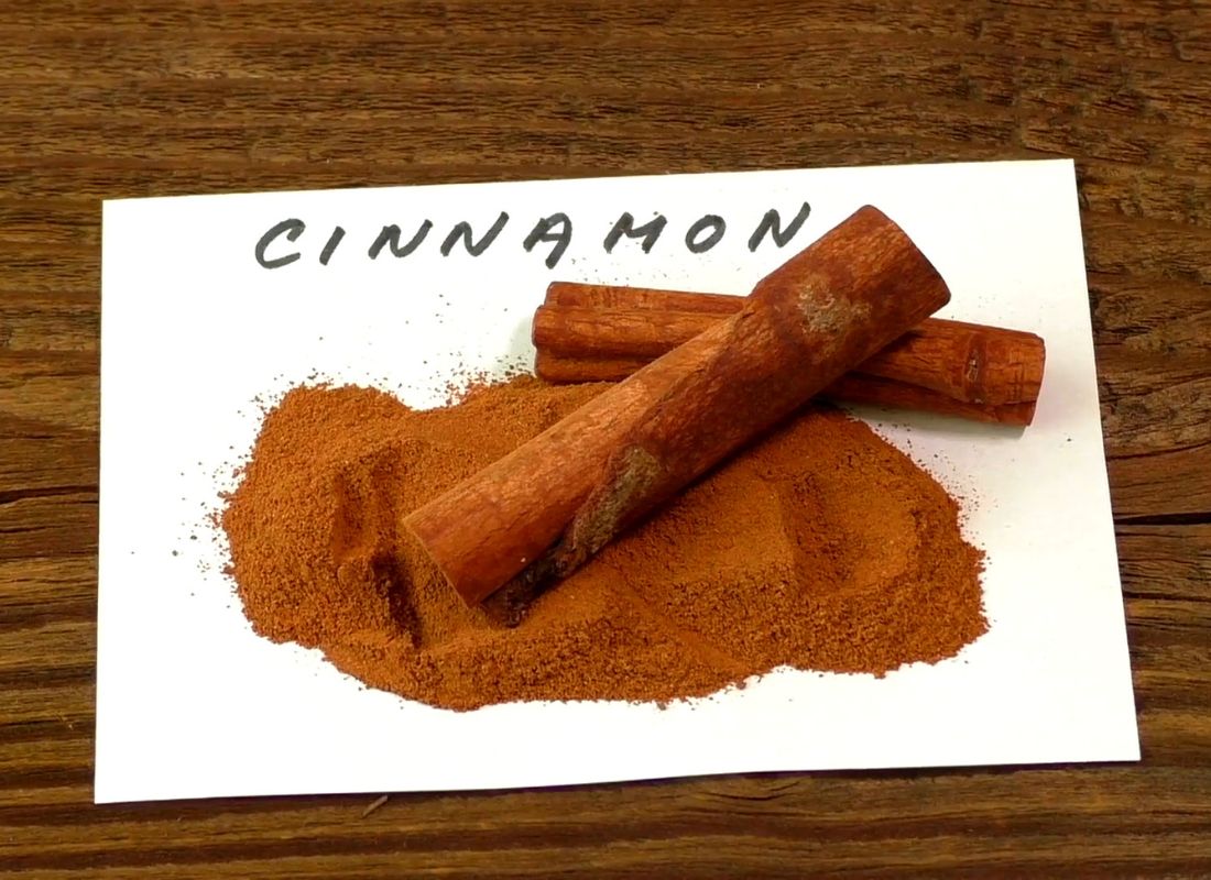 prikaz cimeta u prahu i u štapicu na belom papiru i drvenom stolu