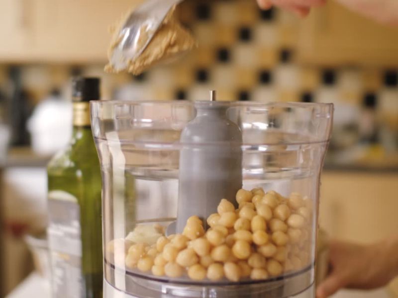 osoba dodaje tahini u leblebije u blender