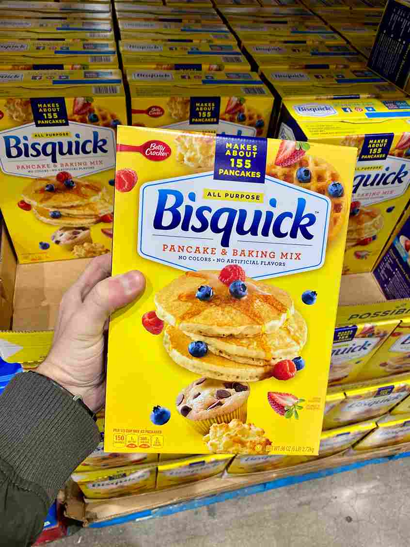 Hand holding a box of Bisquick pancake and baking mix in a grocery store aisle