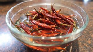 Dried red chilies soaking in a glass bowl of water