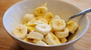 Sliced bananas in a bowl being mashed with a fork.