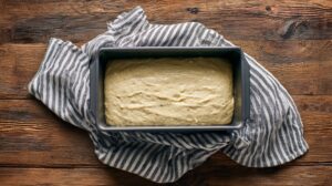 Banana oat bread batter poured into a loaf pan on a wooden surface