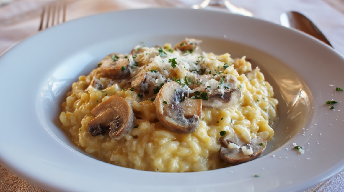 Creamy mushroom risotto topped with herbs and grated cheese on a white plate