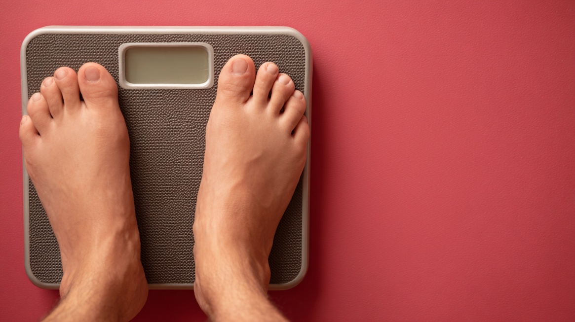 Feet standing on a weighing scale against a colored background