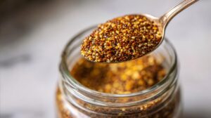 Spoon lifting lightly crushed mustard seeds from a jar
