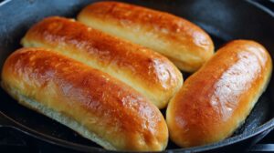 Four split top buns toasted in a skillet until golden brown