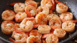Shrimp cooking in a skillet with garlic and herbs