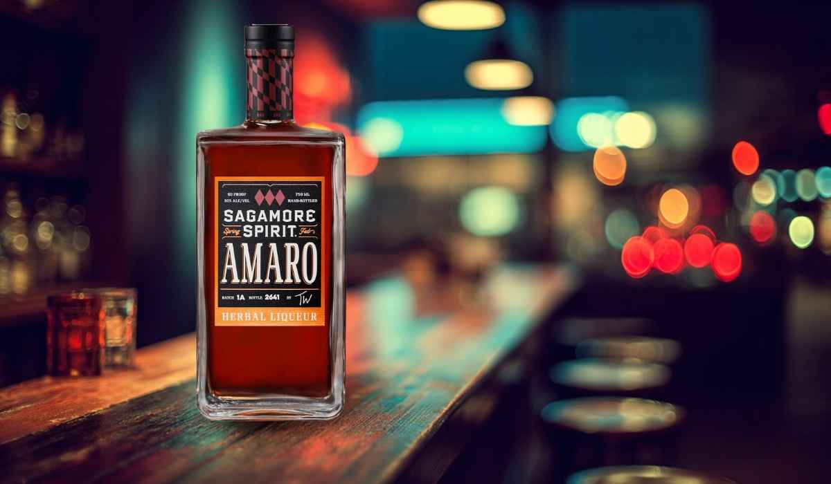Bottle of Sagamore Spirit Amaro herbal liqueur on a bar with colorful blurred lights in the background