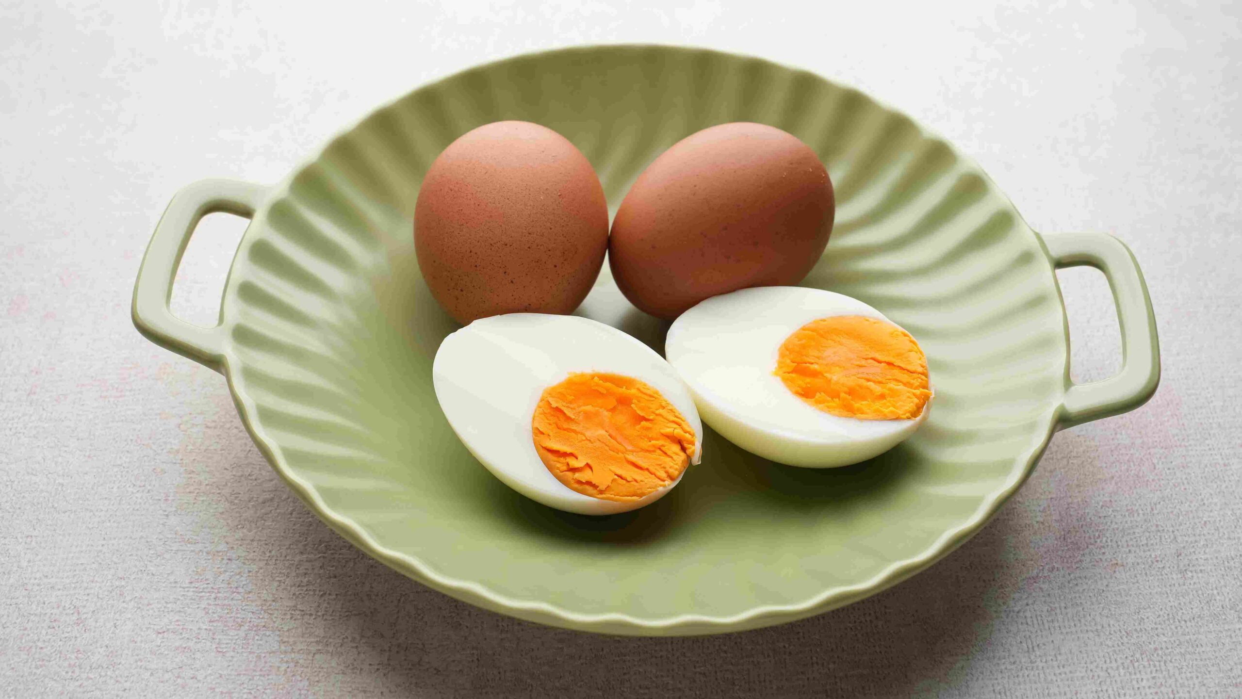 Whole and halved boiled eggs placed in a green dish