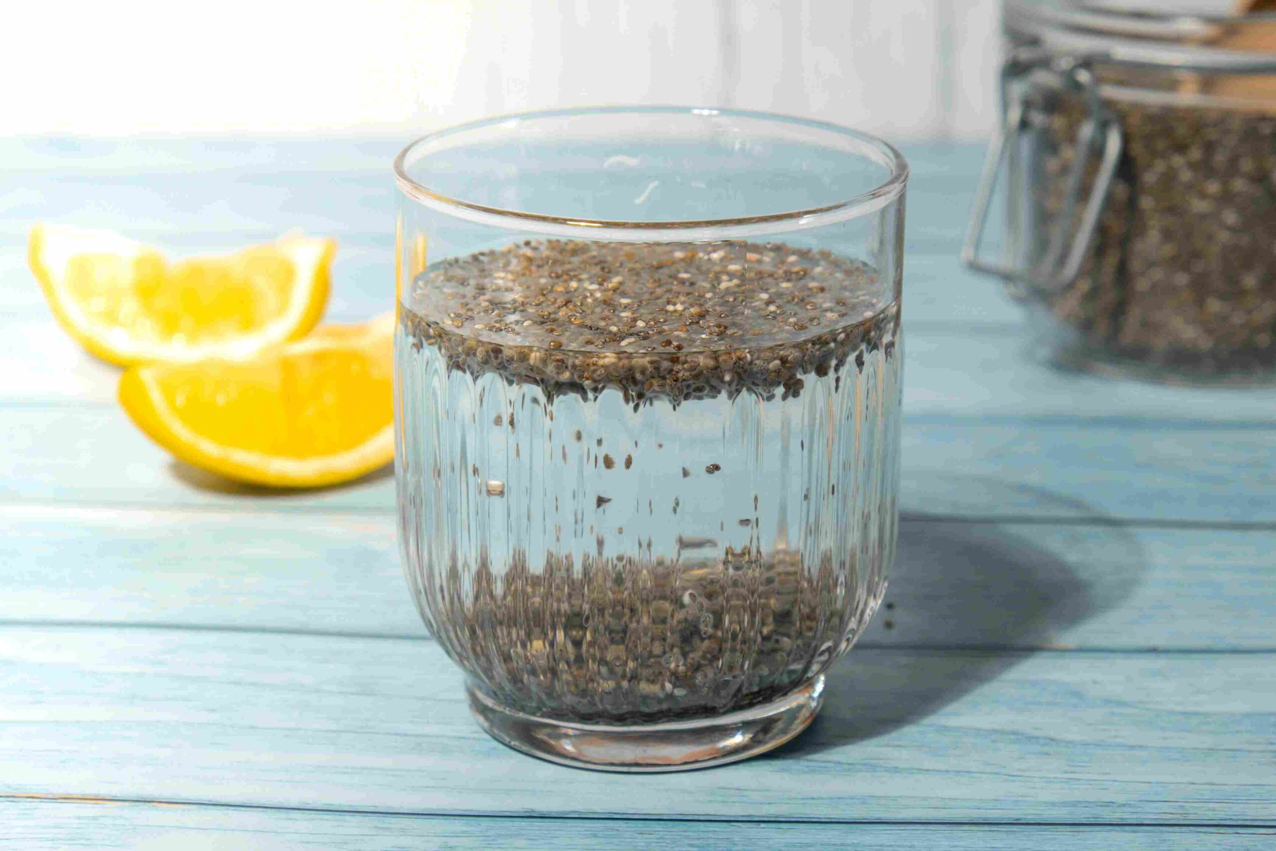Glass of water with soaked flaxseeds and lemon slices in the background