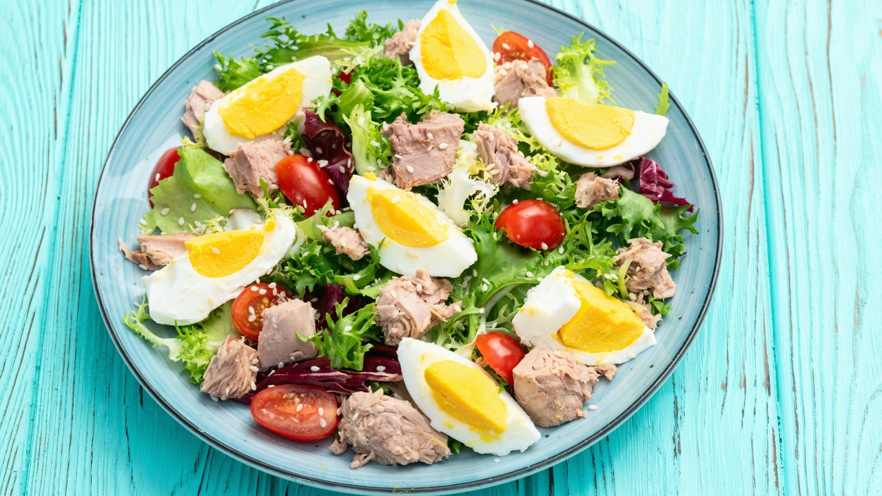 Salata sa kuvanim jajima, tunjevinom, zelenom salatom i čeri paradajzom na tanjiru