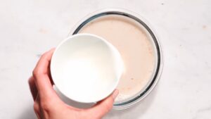 Milk being poured into a bowl of oat mixture