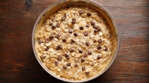 Oat mixture with peanut butter and mini chocolate chips in a mixing bowl