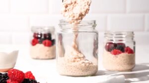 Oat mixture being spooned into jars for portioning