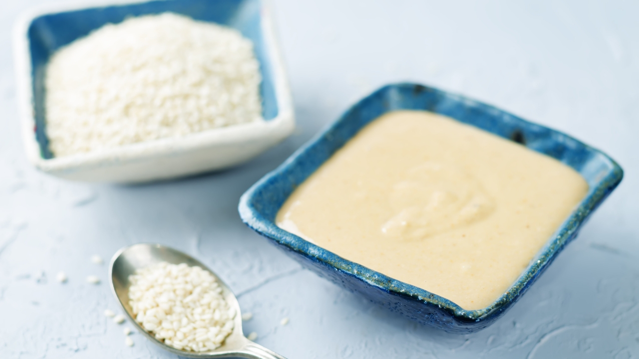 Bowl of tahini with sesame seeds in a dish and on a spoon nearby