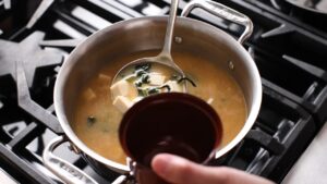 Ladling hot miso soup with tofu and seaweed from a pot into a bowl