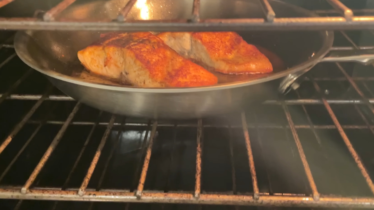 Salmon fillets finish in a stainless steel pan inside an oven
