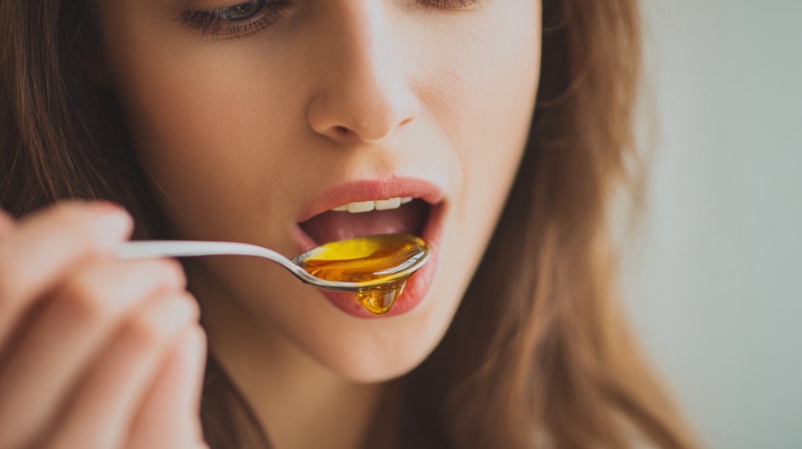 Close-up of a woman tasting honey from a spoon