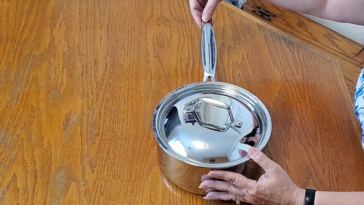 A stainless steel 3-quart saucepan with a lid sits on a wooden table