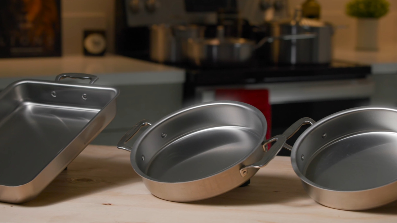 360 Cookware stainless steel pans sit on a wooden counter in a kitchen
