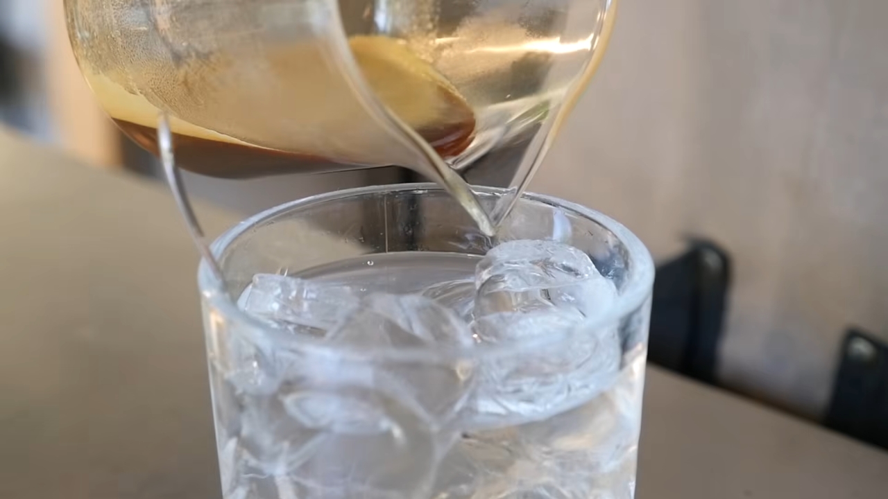 Espresso is poured over tonic water and ice in a clear glass