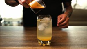 Espresso being poured into a glass of tonic water, orange juice, and ice