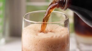 Cold cola being poured over ice into a glass for dirty soda.
