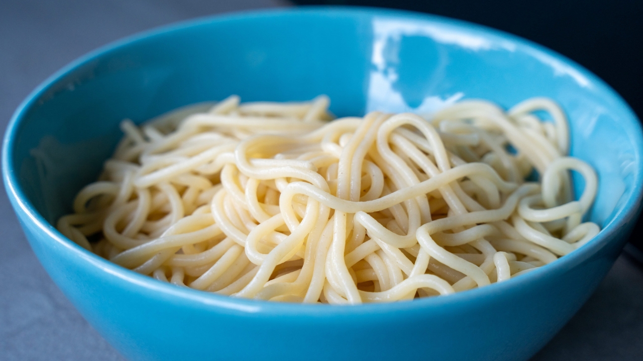 Cooked spaghetti in a blue bowl.