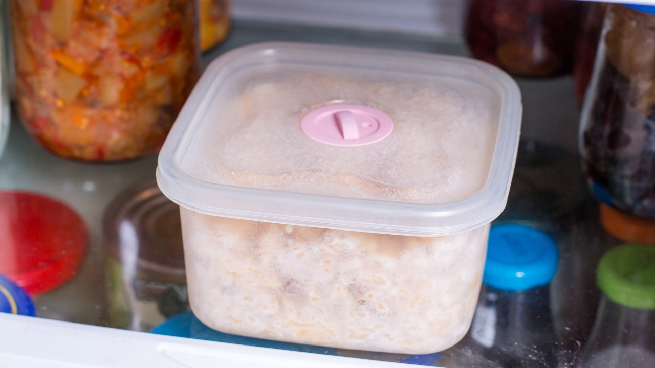 Cooked pasta stored in a sealed plastic container inside a refrigerator.