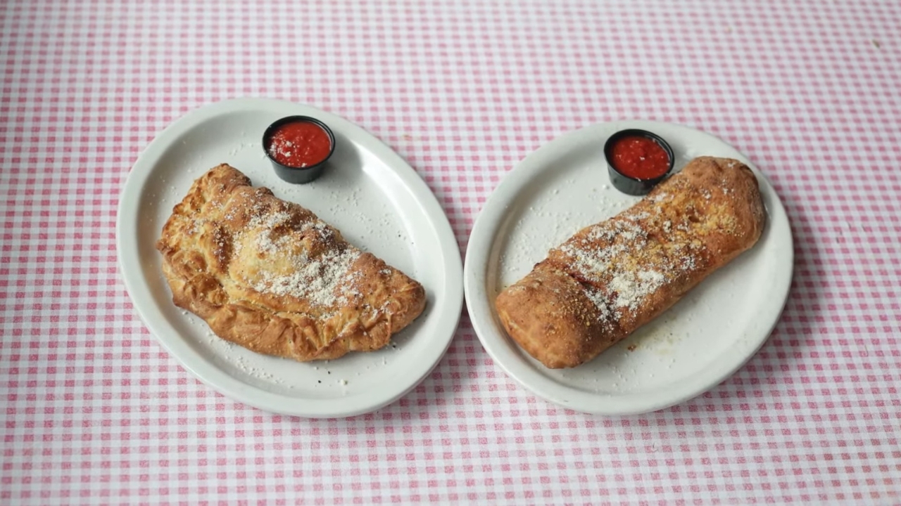 Calzone and stromboli served on separate plates with marinara sauce.