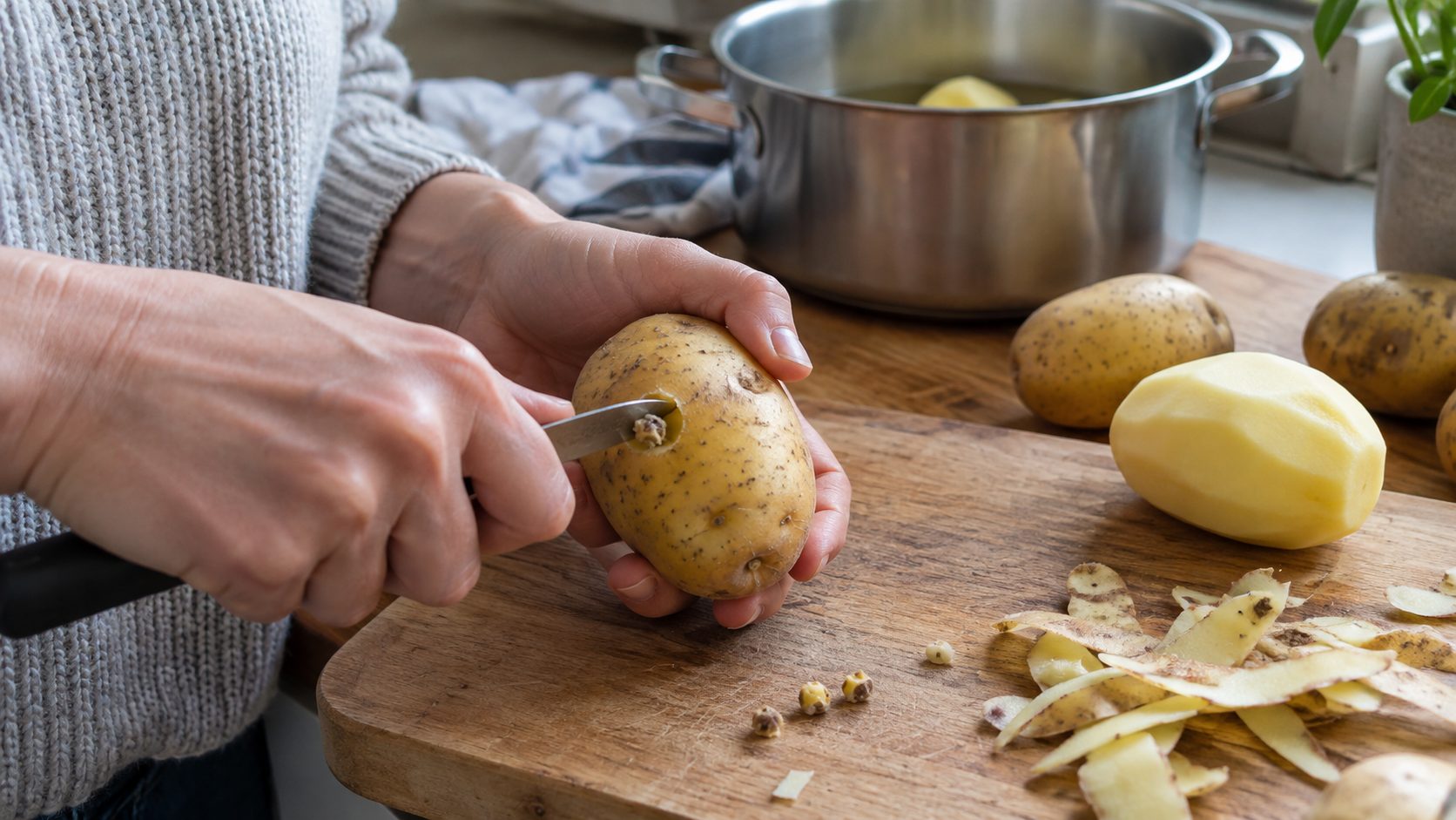 Person using a small knife to remove a potato sprout before peeling and cooking.